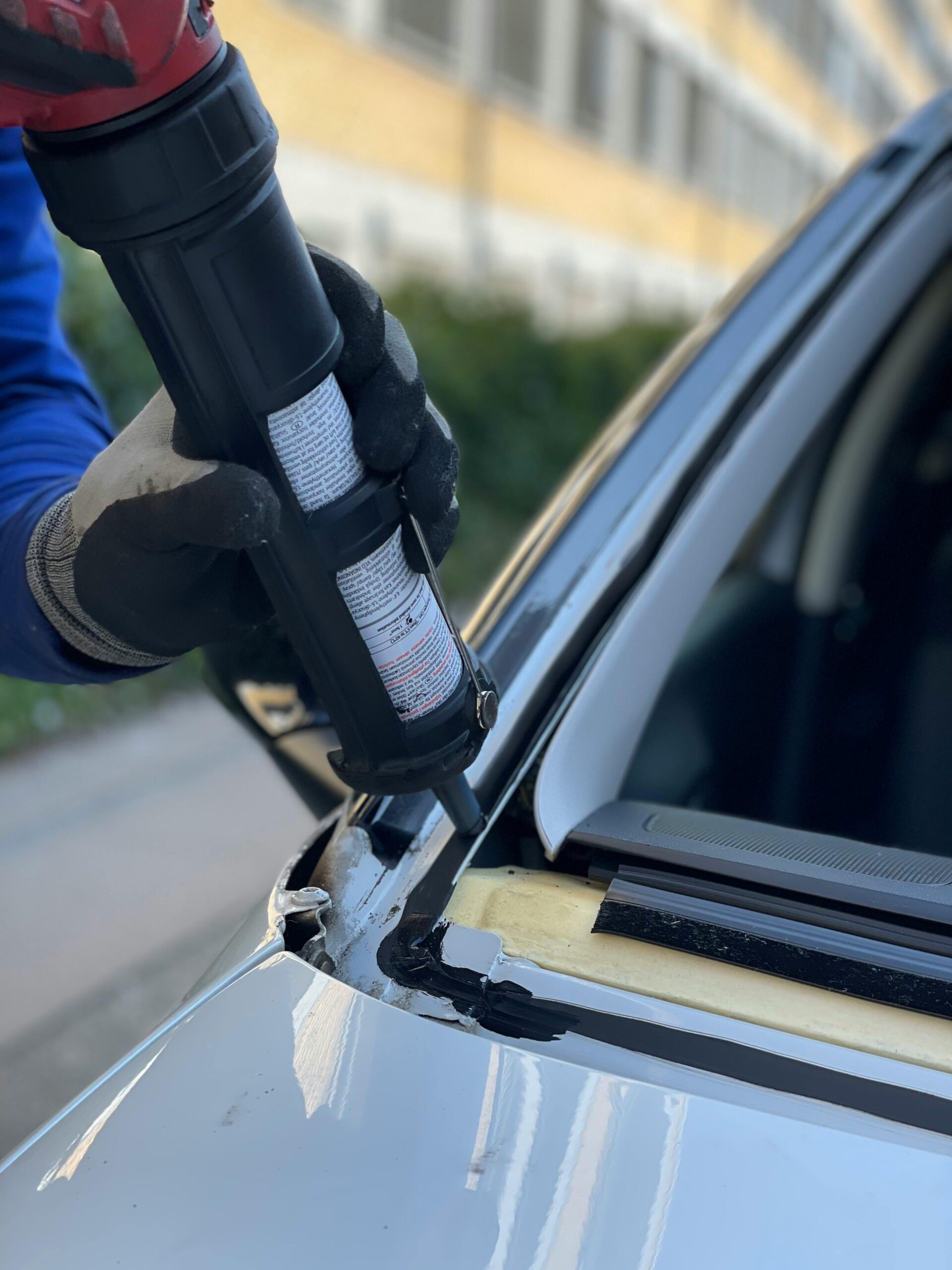 Close-up of a technician repairing a car windshield in a Copenhagen workshop.